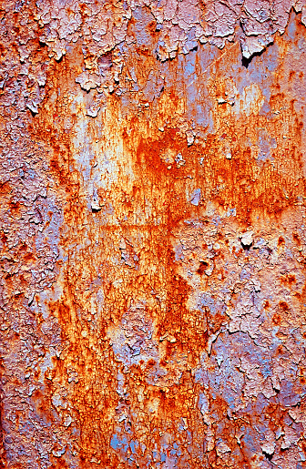 Close-up of peeling paint on a weather ravaged metal surface of an electrical junction box forming a colorful, textured abstract