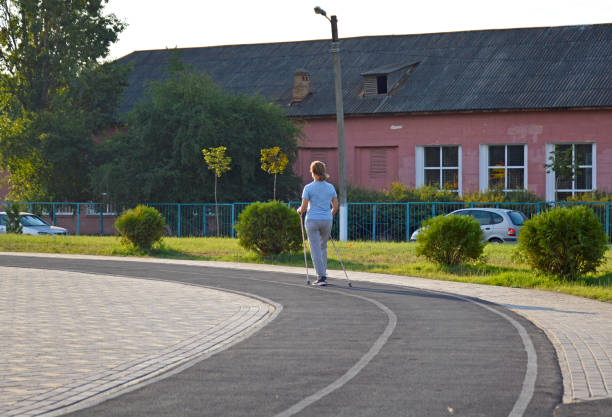 young woman doing Nordic walking. a woman walks on a rubber track around the school stadium. active lifestyle. physical education and sports