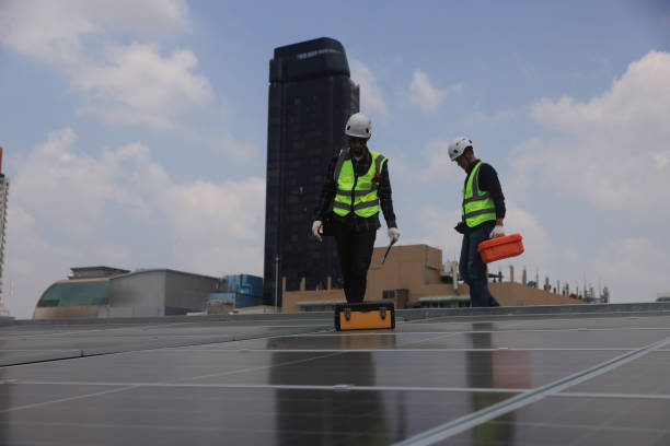 istock Specialist technician professional engineer with a safety vest and toolbox checking to install solar roof panels on the factory rooftop under sunlight. Engineers team survey check solar panel roof. 2151163983