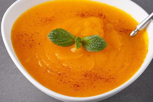 Pumpkin soup on grey background.