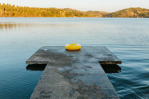 Calm atmosphere on a beautiful lake and Inflatable ring placed on a pier , after children playing with it