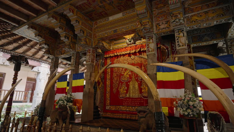 Interior of Sri Dalada Maligawa, Kandy. Sacred area with golden shrine, colorful flags. Worship space in Buddhist temple with intricate wood carvings, historical art. Religious tourism.