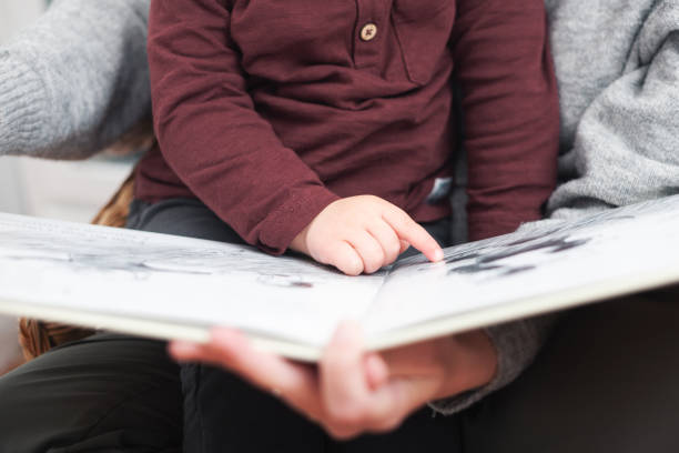 istock A child pointing at a book while a parent reads it 2151175036
