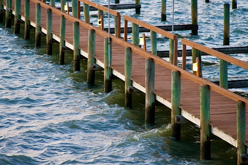 Chincoteague, Virginia, USA - March 30, 2024: Water laps against a wooden pier at high tide on a cool spring evening.
