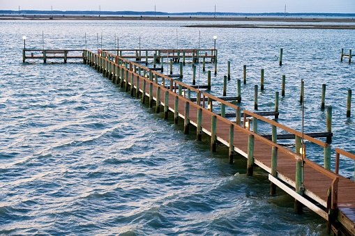 Chincoteague, Virginia, USA - March 30, 2024: Water laps against a wooden pier at high tide on a cool spring evening.