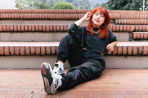 Casual Korean woman with red hair lounging on city stairs