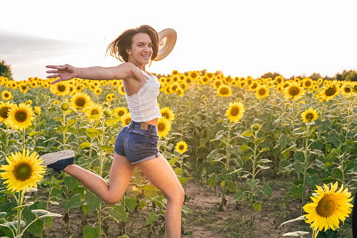 Gen Z girl having fun at sunset in yellow Sunflower field. Happiness and joy.