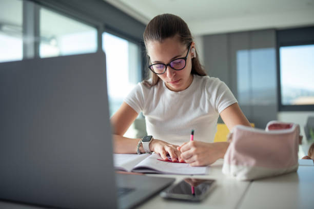 istock College student doing some home works from home with laptop. 2151185735
