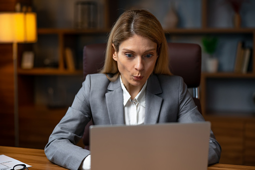 Business problem. Shocked female entrepreneur looking at computer monitor, reading awful news online, sitting in office. Entrepreneurship issues concept