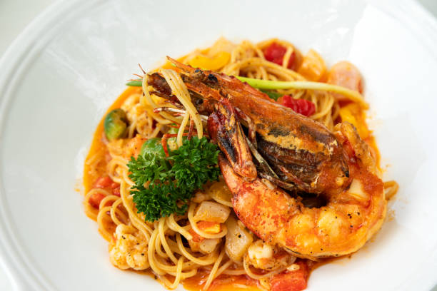 Delicious spaghetti pasta served with succulent shrimp, fresh parsley, and savory tomato sauce, presented elegantly on white plate
