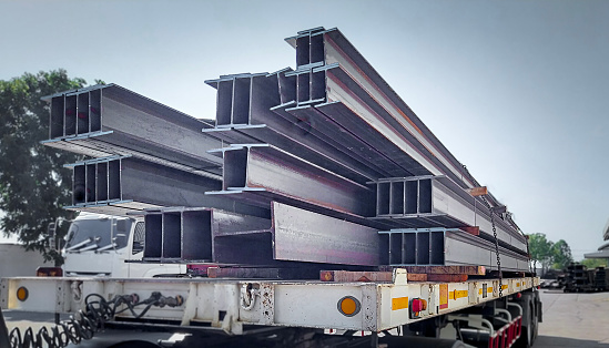 Trucks with long trailers carrying steel bars for building construction. Construction steel is ready to be delivered to the customer. Beam Steel in thailand