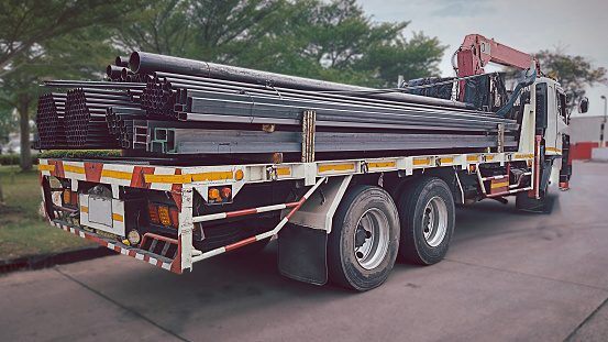 Trucks with long trailers carrying steel bars for building construction. Construction steel is ready to be delivered to the customer.Steel in thailand