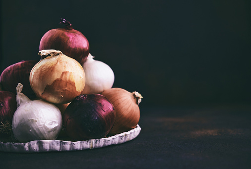 A collection of onions in a dark setting
