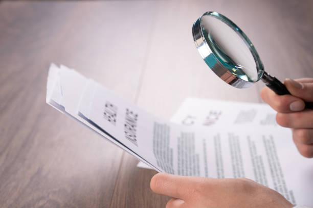 istock A man examines papers with a magnifying glass 2151196416