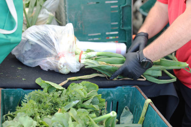 Spring onions for sale at the market. Unrecognizable crowd of people shopping for vegetables. Auckland.