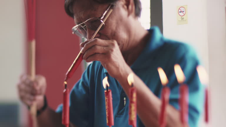 Elderly man lighting up joss stick