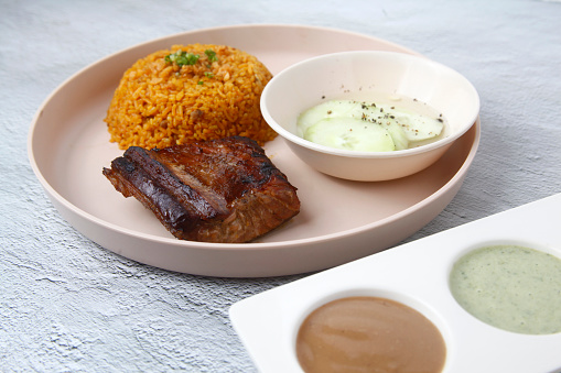 Photo of freshly prepared grilled tuna belly served with rice and assorted dips and sauces.