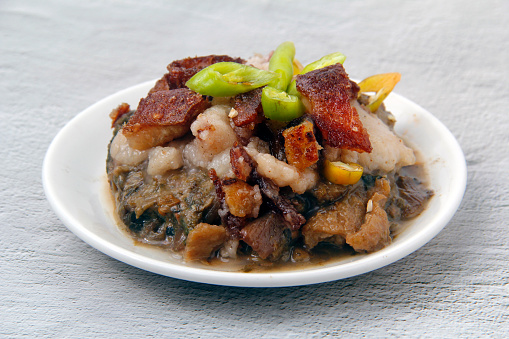 Photo of freshly cooked Filipino dish called Laing with Lechon or taro cooked in coconut milk topped with crispy pork.