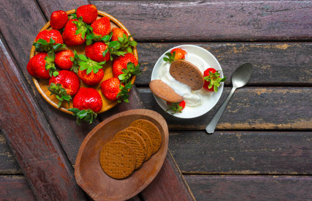 Detailed view of fluffy pancakes topped with fresh strawberries, whipped cream, and mint leaves, presented on a plate with a knife, messy food
