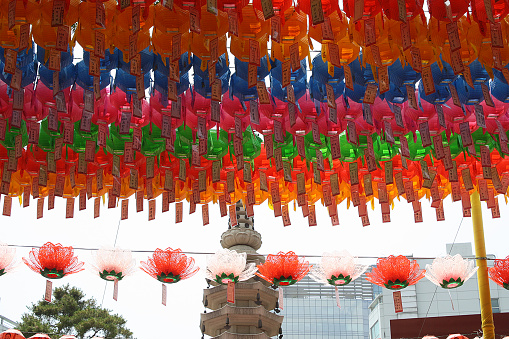 A picture of colorful paper lanterns over a string of red and pink lotus flower lanterns at the historic Bongeunsa Temple in Seoul, South Korea.