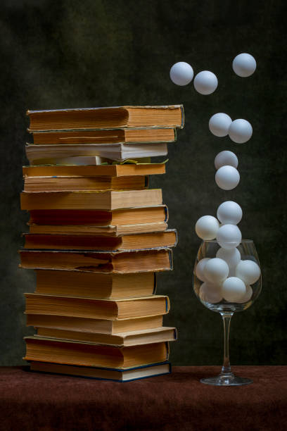 Still life with a stack of books and white balls in a glass