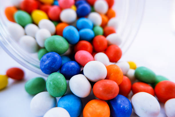 Mixed collection of colorful candy, on isolated white background. Flat lay, top view, front view.  A jar of colorful chocolate coated candy.