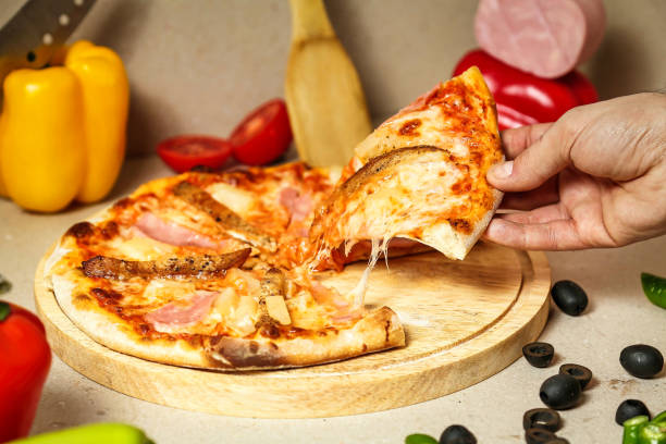 istock Person Taking a Slice of Pizza From a Cutting Board 2151214804