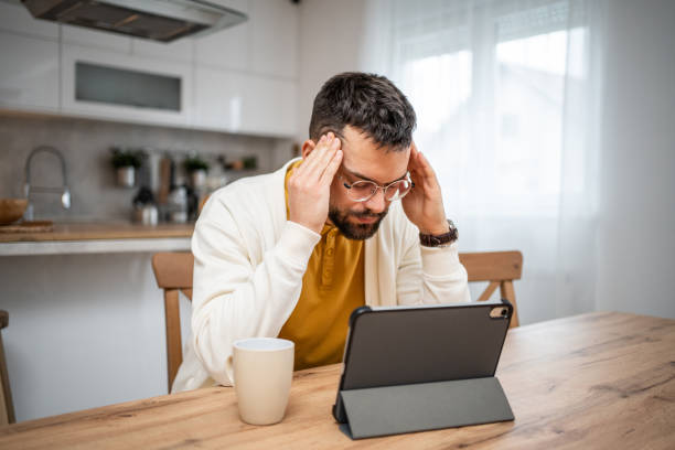 istock Worried and tired man using digital tablet at home 2151215846