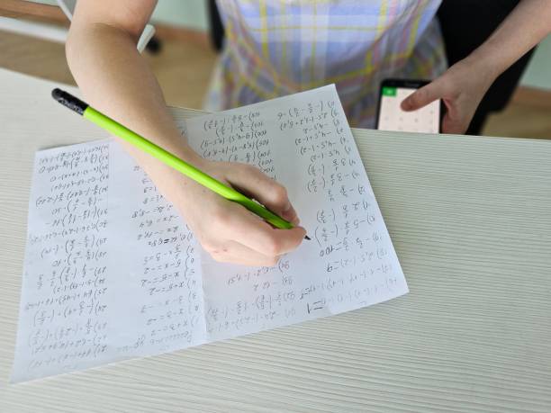istock Student child holding smartphone during control exam test at school and cheating on the exam. Write off cheat sheet in lesson or exam 2151216513