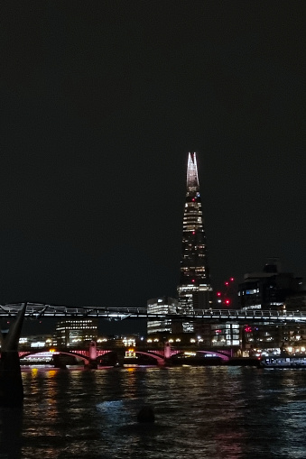 London, United Kingdom, March 24, 2024: Nighttime Cityscape with Illuminated Skyscraper and Bridge over River.