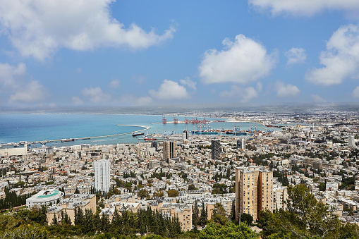 Seaport in the city of Haifa, panorama of the port and city buildings against the background of a blue sky with clouds.