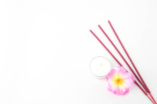 Isolated Empty white background decorated with colorful flowers, red colored incense and round white candle. Concept for Vesak Day and Enlightenment Day. Empty blank copy text space