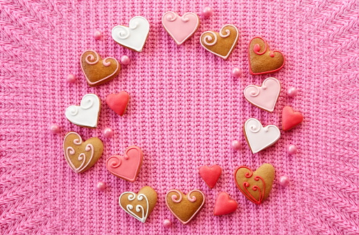 Gingerbread hearts frame on pink knitted sweater background
