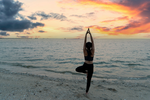 Young fit woman practicing yoga .sunset and silhouette