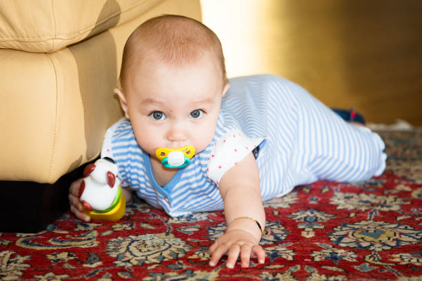 A cute little girl learns to walk, sneaking very quickly even on the carpet at home.