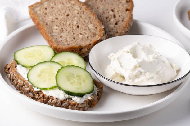 istock Rye bread with cream cheese and cucumbers on a white table. Whole grain rye bread with seeds 2151223571