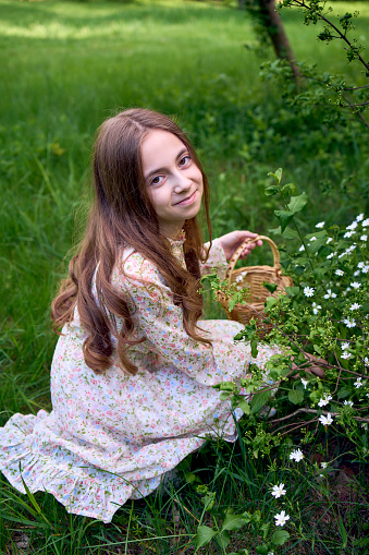 llittle girl with long hair collects flowers in an Easter basket