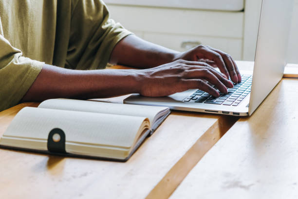 istock Close-up of Hands Typing on Laptop Keyboard with Notebook on Desk 2151225663