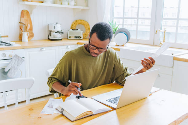 istock African American Man Working on Finances with Laptop and Receipts in Bright Kitchen 2151225977