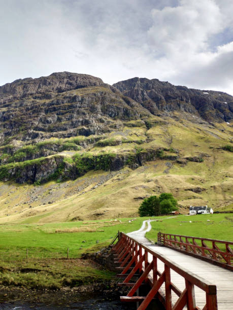 istock Scottish highland nature scenery, mountain top surrounded by clouds, grazing in streams and rivers, sheep grazing, red bridge across the river 2151226035