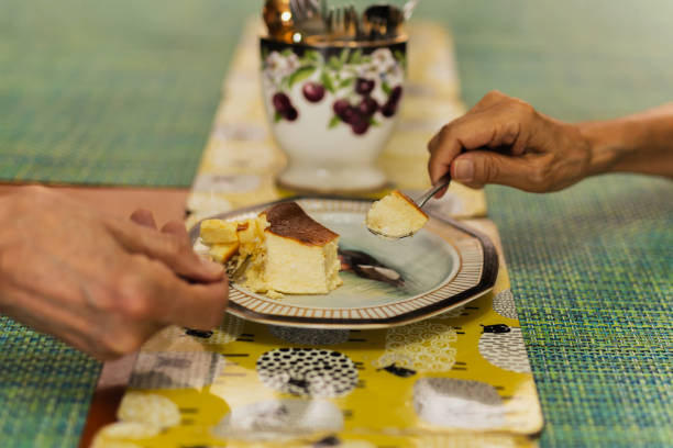 istock Senior couple hands with spoon eating burnt cheesecake. 2151227919