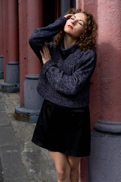 istock Young female model posing with closed eyes and leaning on column. 2151228443