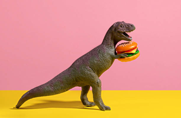 istock Happy dinosaur holding burger on pink and yellow background. 2151229461