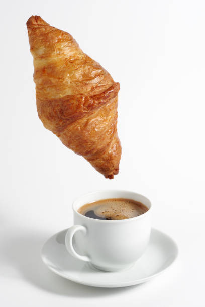 istock Croissant hanging over coffee 2151243828
