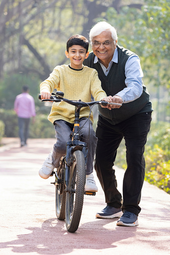 Boy learning bicycle with assistance of grandfather at park