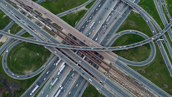 Aerial urban spectacle, metro train cuts through traffic-heavy highways, commuters in constant motion. Aerial view where metro train intersects with vehicular veins, showcasing urban flow diversity