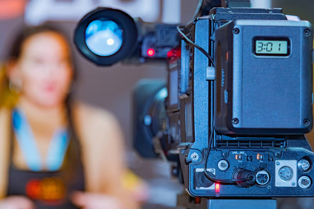 istock Camera is shooting a girl. Shooting on a professional camcorder. Recording a news plot. Concept - work leading news. Concept - work on television. Camcorder at the time of recording the report 2151244974