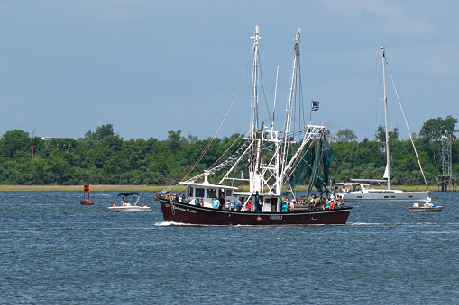 Charleston, SC, USA - April 28, 2024: Richardson Brothers fishing trawler sails in the boat parade during the annual Blessing of the Fleet in Charleston Harbor.