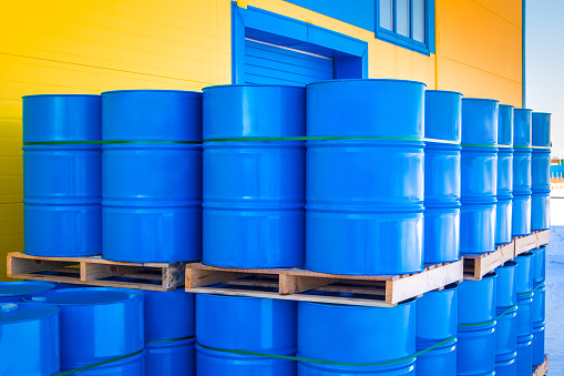 Blue containers loaded on pallets. Plastic barrels for toxic products. Chemical storage tanks. Barrels for shipment from stock. Transport of hazardous substances. Warehouse work. Logistics in stock.