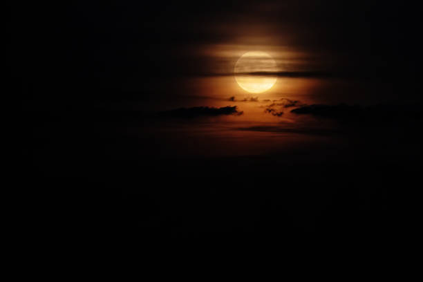 Full Moon in dark clouds against a black sky. Natural night sky scenery. . Moon in the style of mystical and thrillers